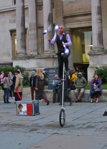 A juggling uni-cyclist , performing in front of the National Gallery...